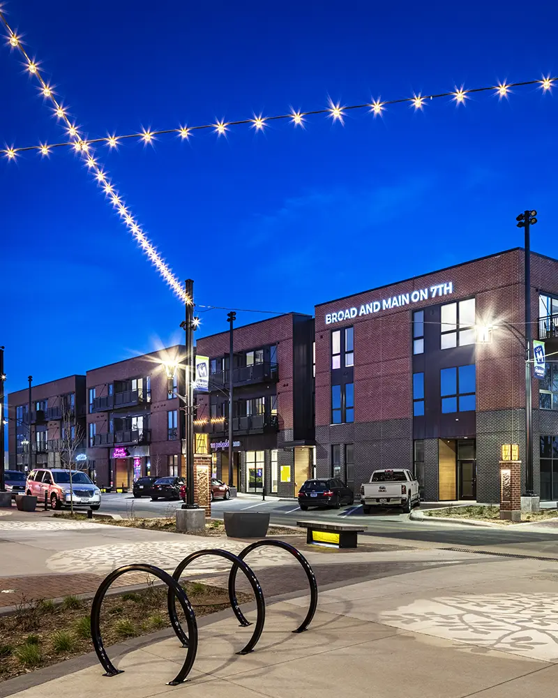Nighttime in a pedestrian plaza with building across the street.