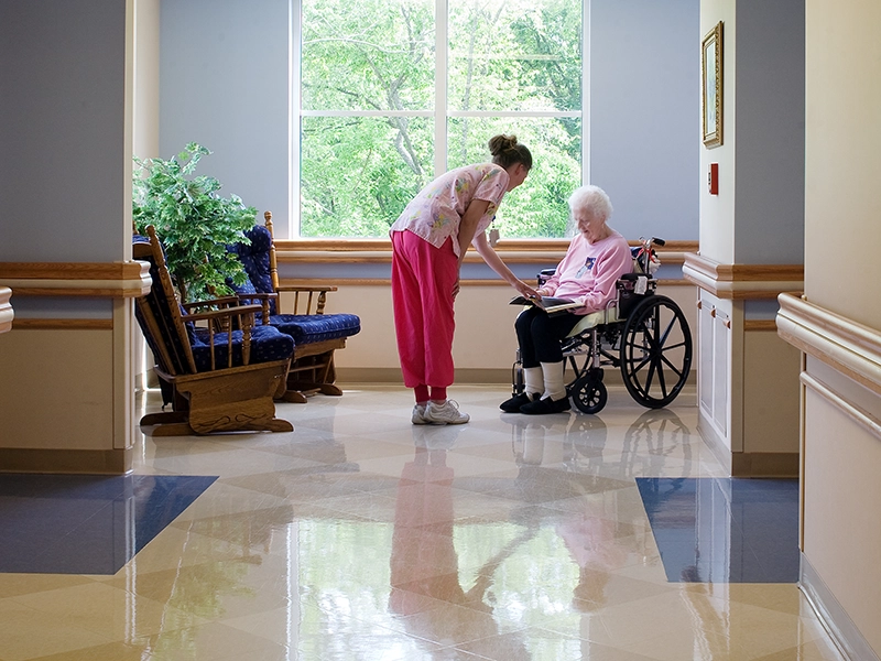 Care center hall with resident in wheelchair and staff