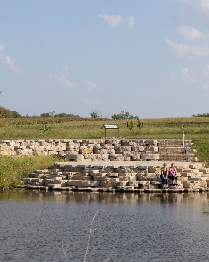 People sitting on stone structure overlooking lake