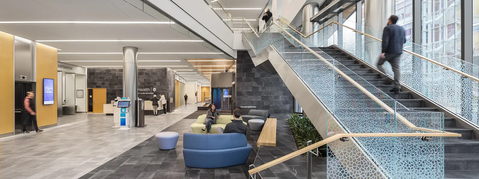 Hospital lobby, waiting area with elevators and open stairway with glass.