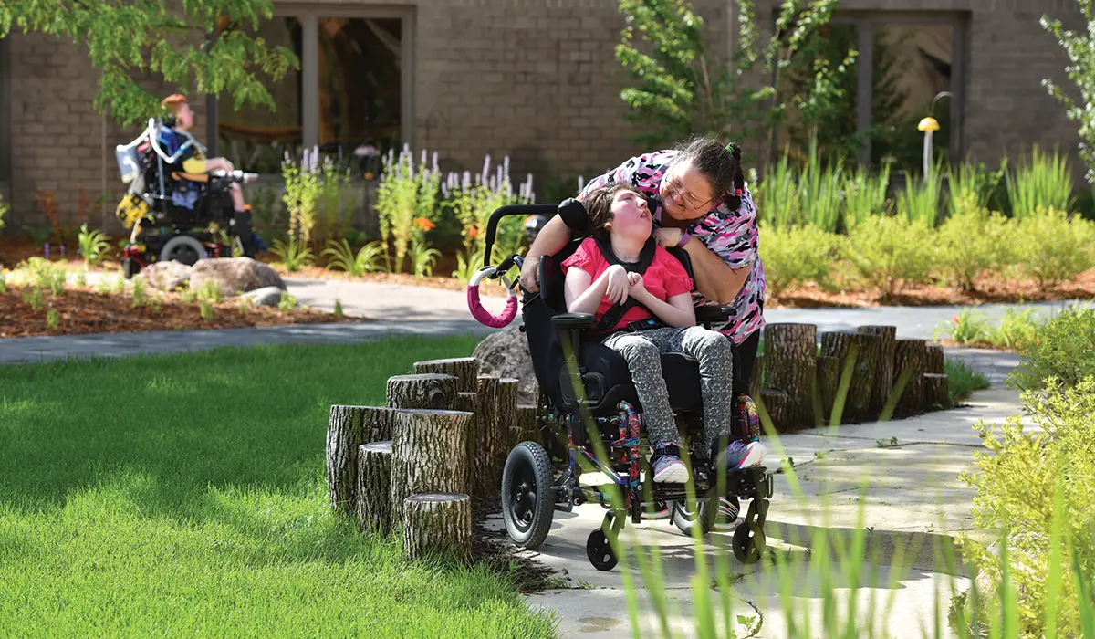Child in wheelchair and caregiver in ChildServe Healing Garden