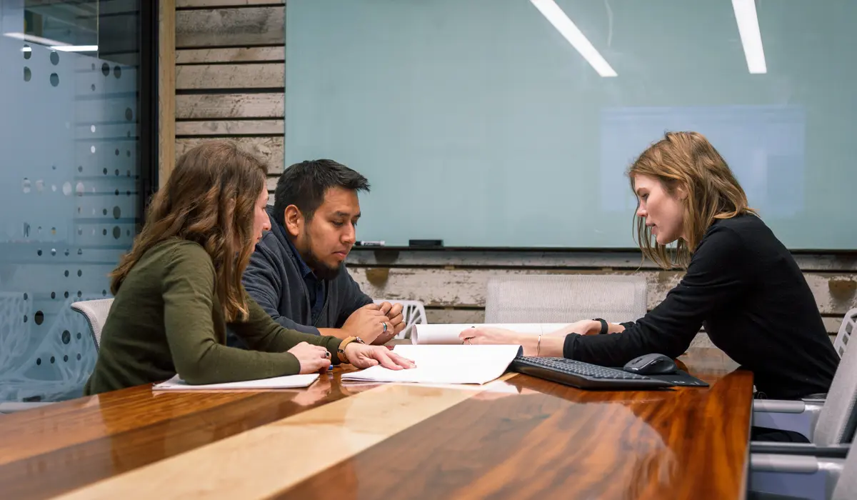 Group of three people working over designs