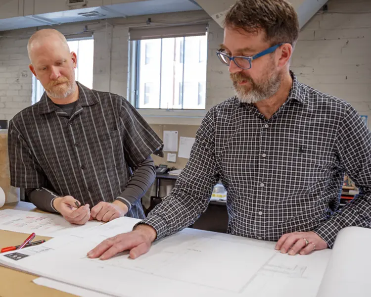 Two Men working over blueprints