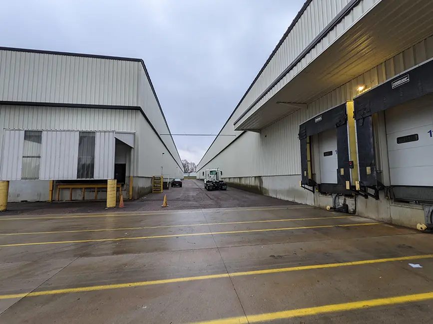Exterior view of two industrial warehouse buildings with loading docks and a clear driveway.