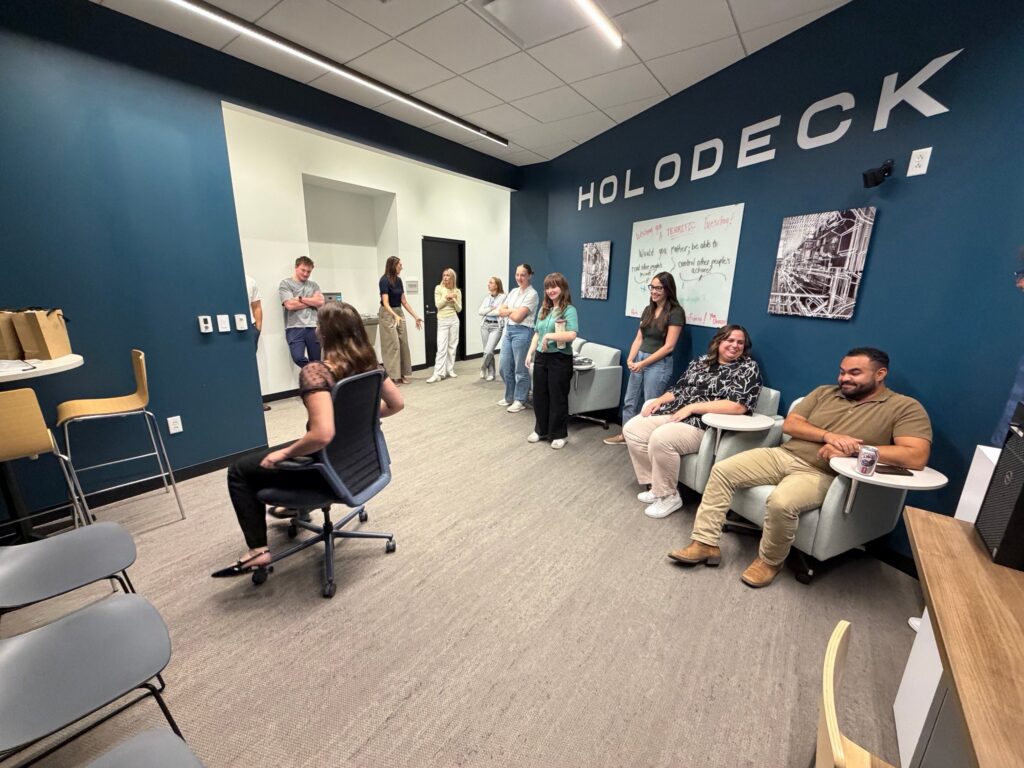 A coworker swivels in the KI chair as colleagues watch in the Holodeck at Shive-Hattery Quad Cities