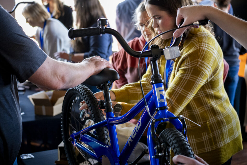 Corporate team members assembling bicycles together during a team-building activity at the 2026 Corporate Swarm